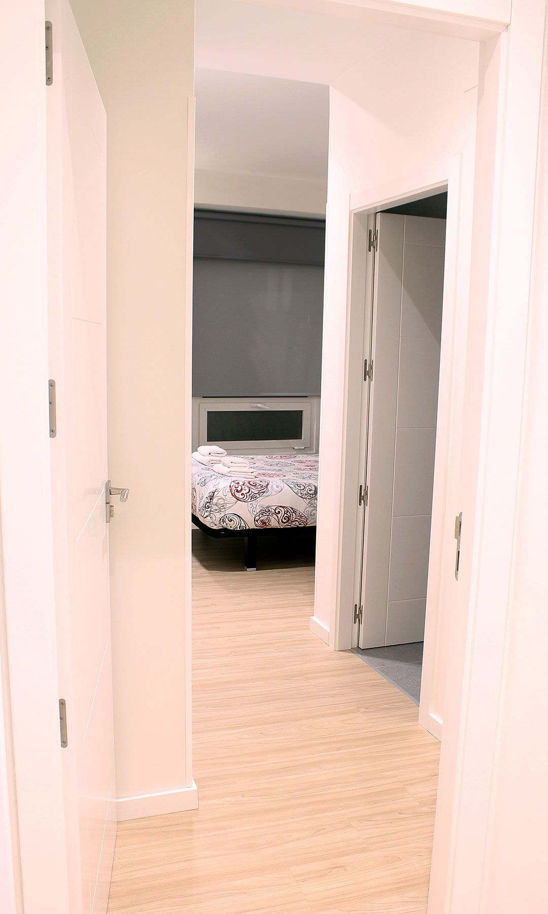 Een slaapkamer met een bed, een kledingkast en een deur naar een andere kamer.