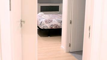 Een slaapkamer met een bed, een kledingkast en een deur naar een andere kamer.
