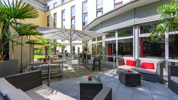 An outdoor patio area with tables, chairs, and a sofa. - PhiLeRo Hotel Köln (Cologne)