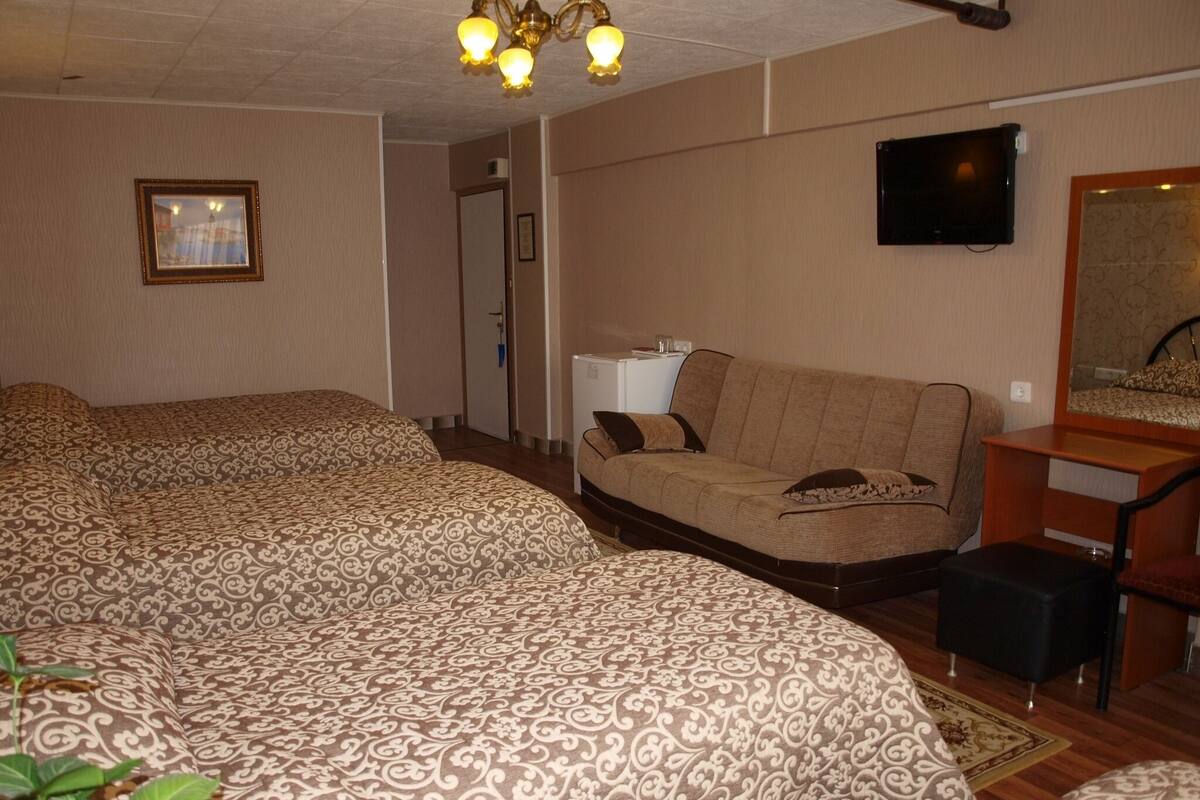A hotel room with a large bed, a sofa, a television, and a desk.