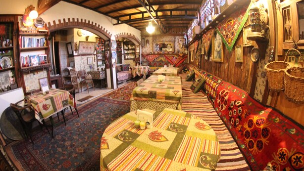 A cozy interior with a long bench, tables, and a bookshelf.