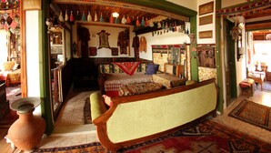 A traditional room with a sofa, patterned rugs, and various decorative items.
