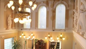 Un intérieur somptueux, agrémenté d’un lustre, de grandes fenêtres et de statues classiques.