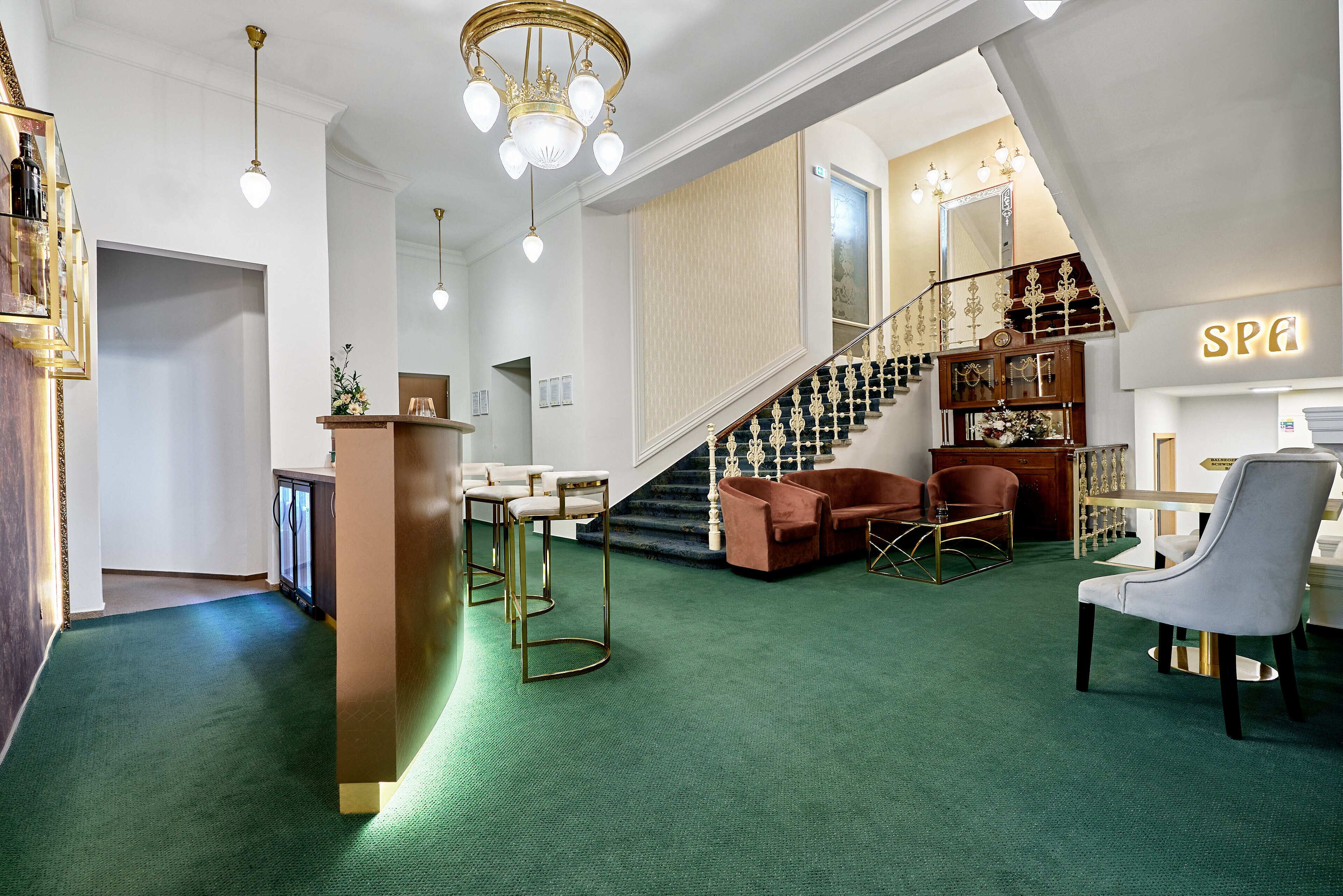 Eine moderne Hotelhalle mit grünem Teppich, einer Treppe und einem Schild für das Spa.