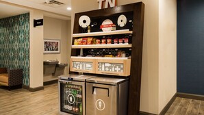 A vending machine area with snacks and beverages, a sign indicating the elevator, and a wall with a geometric pattern. - Hampton Inn Newport (Newport)