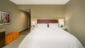 A hotel room with a large bed, a nightstand with a lamp, a phone, and a painting on the wall. - Hampton Inn Newport (Newport)