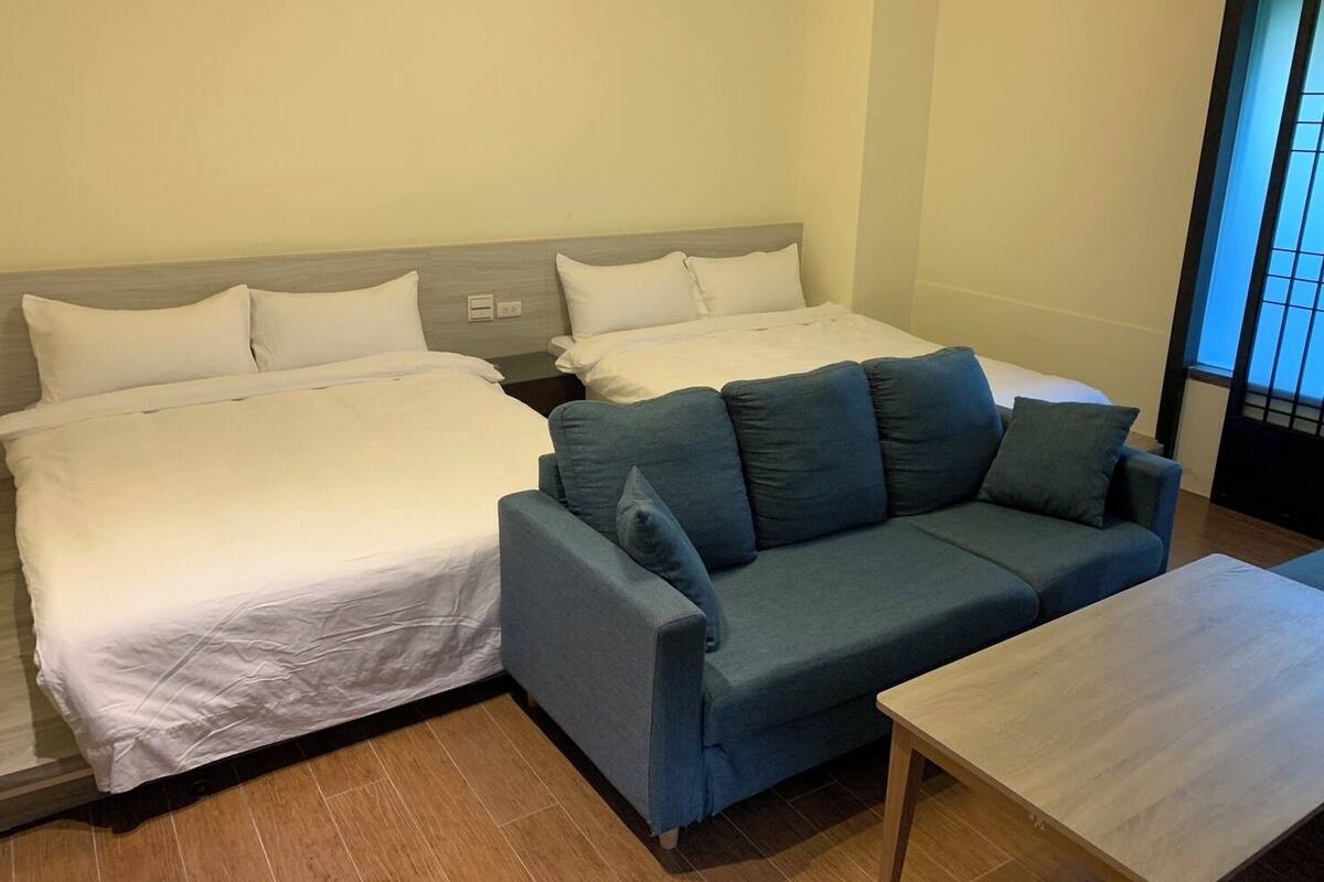 Een hotelkamer met twee bedden, een bank en een kleine tafel.