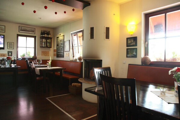 A cozy restaurant interior with wooden furniture, a fireplace, and a wine rack. - Villa Rozmaryn (Tri Sekery)
