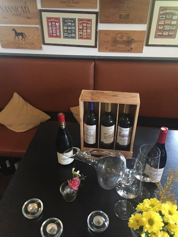 Een gedekte tafel met wijnflessen, glazen en een bloemstuk in een restaurant.