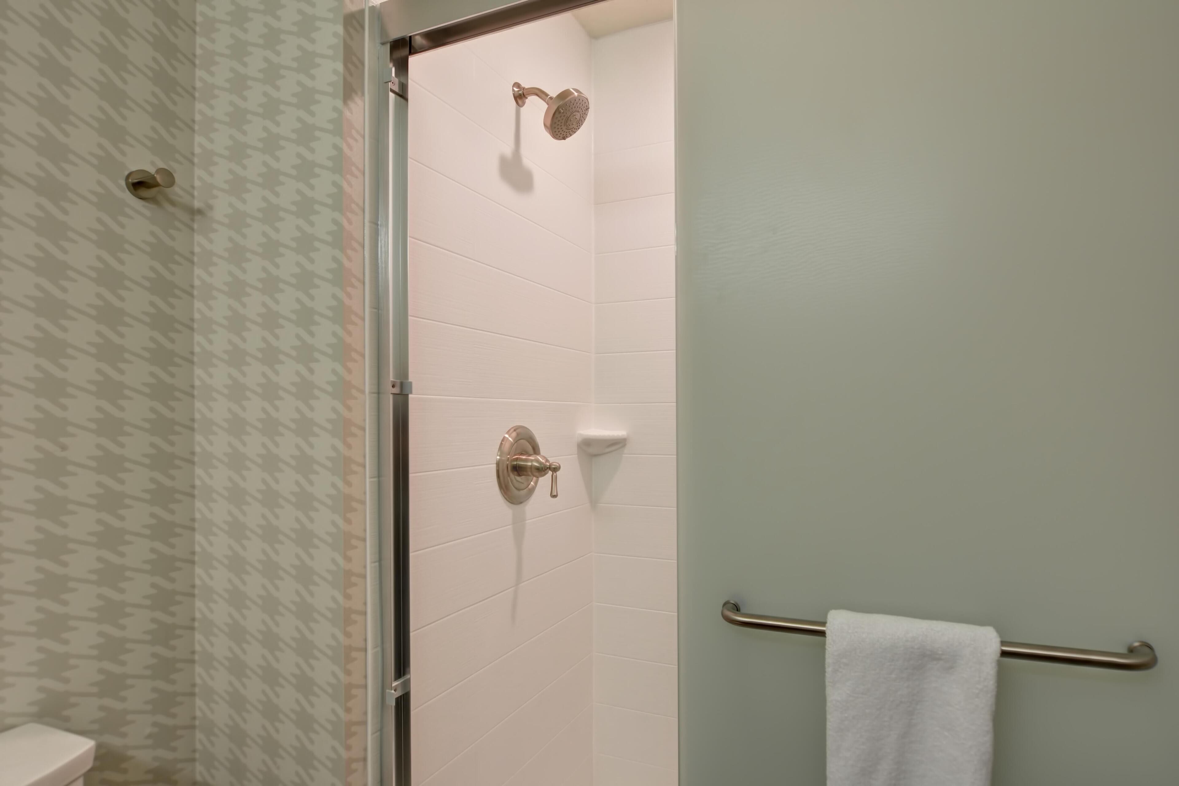 A bathroom with a shower, toilet, and towel rack.