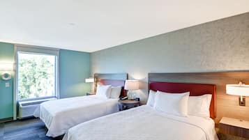 A hotel room with two beds, a window with a view of trees, and a marble-patterned wall.