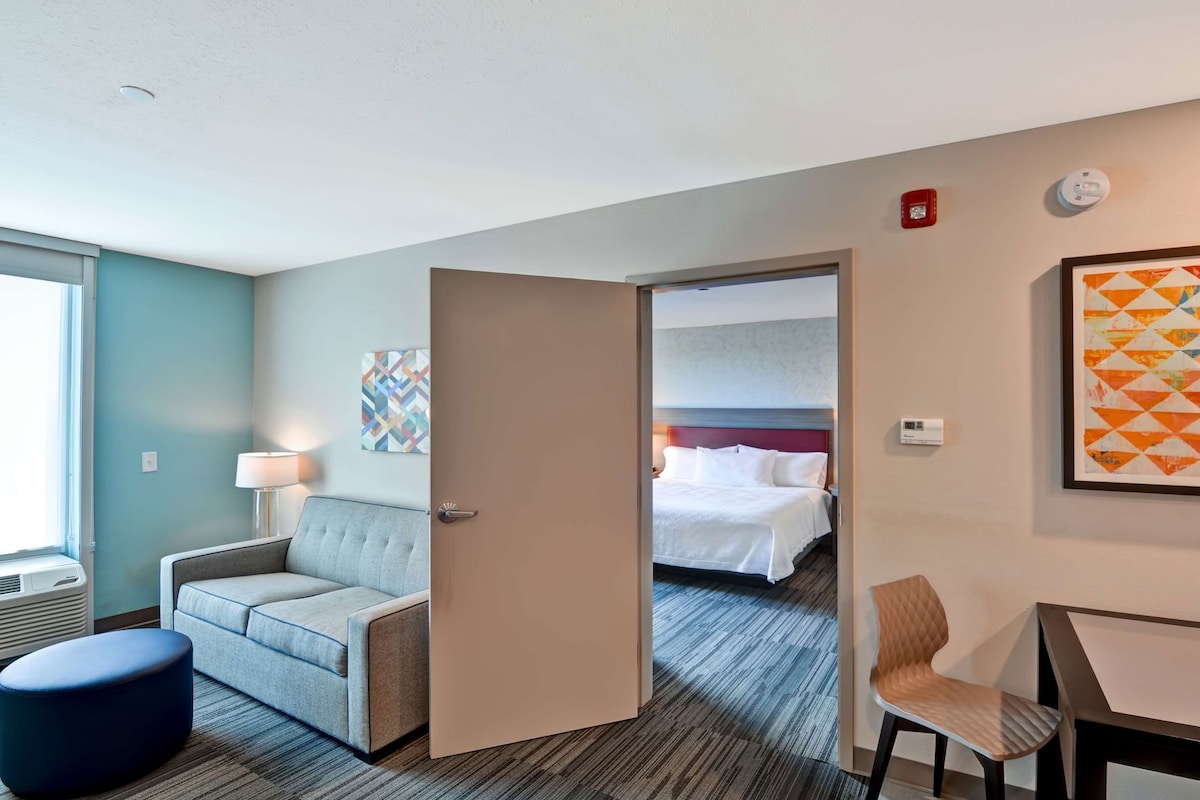 A hotel room with a sofa, a chair, a bed, and a desk.