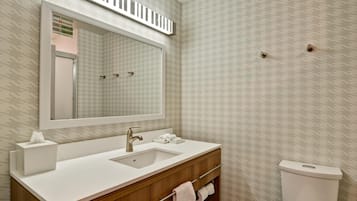 Un baño con lavamanos, espejo y retrete blancos.