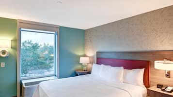 Een hotelkamer met een groot bed, een raam met uitzicht, een nachtkastje met lamp en een telefoon op de nachtkast.