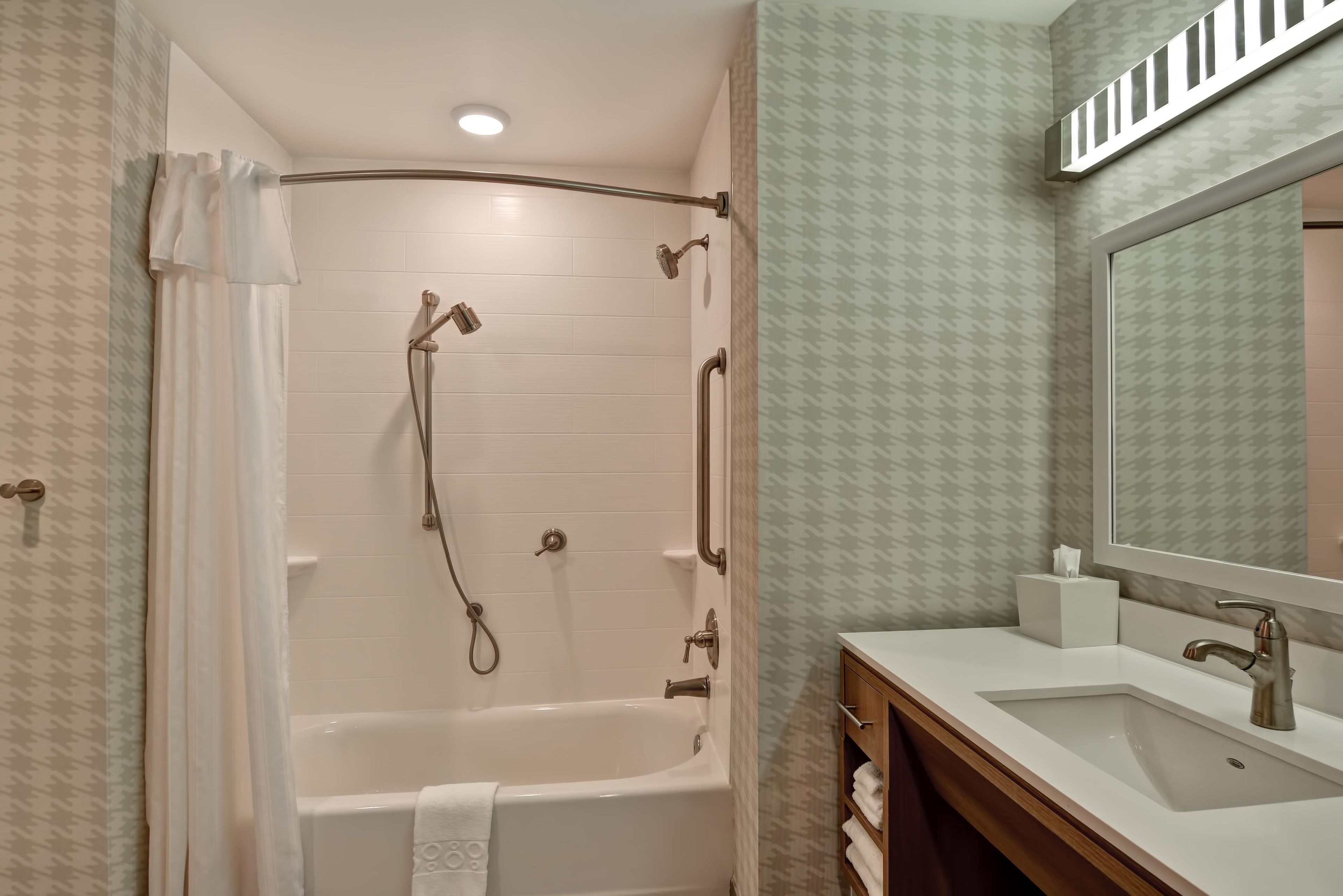 Un baño con ducha a nivel de suelo, bañera, tocador con espejo y toallero.