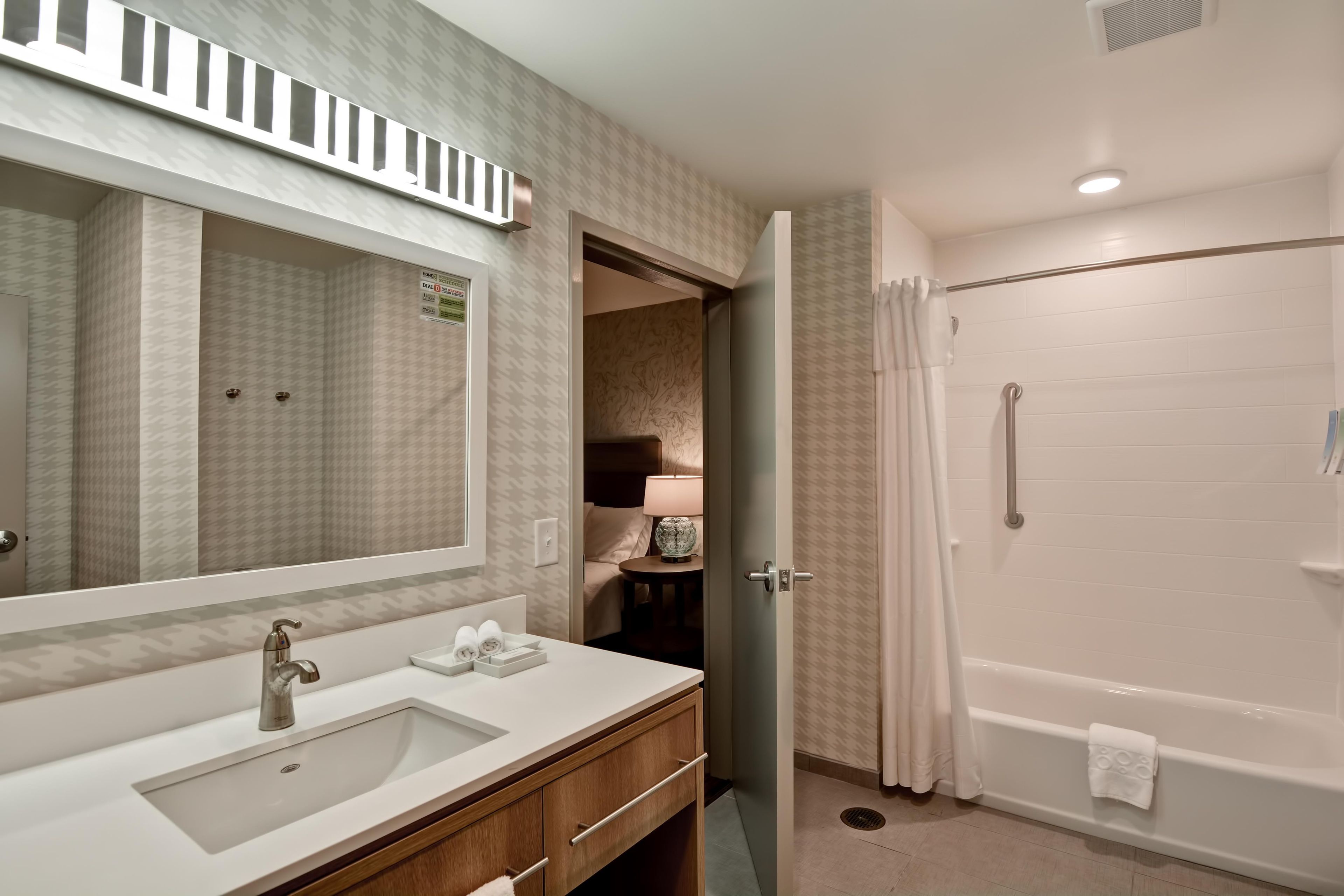 A bathroom with a large mirror, sink, and a walk-in shower.