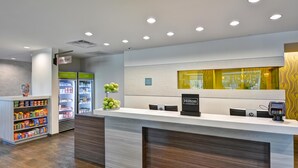A hotel reception area with a counter, vending machines, and a sign indicating 'Hilton Honors'. - Home2 Suites by Hilton Tampa USF Near Busch Gardens (Tampa)
