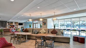 Un interior moderno con una zona de estar, una barra de café y ventanas amplias.