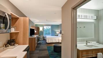 Habitación de hotel con kitchenette, cama, baño y vistas al exterior.