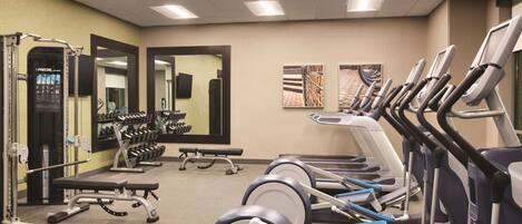 A gym with treadmills, weight machines, and a bench.