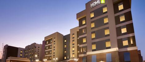 A multi-story hotel with a prominent "HOME 2" sign, featuring a modern architectural design with a mix of brick and glass facades.