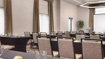 A conference room with multiple tables, chairs, and a projector screen.