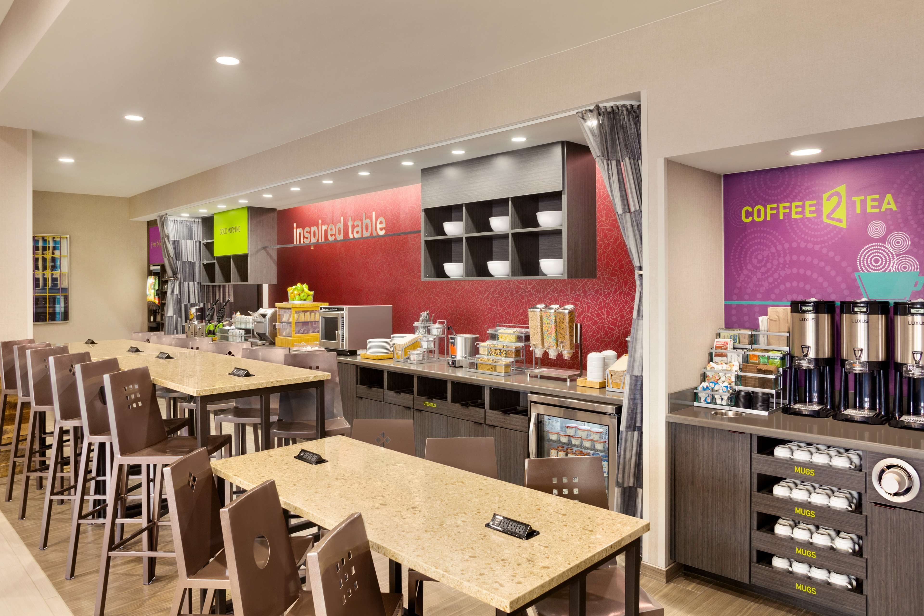 Um café moderno com diversas áreas de estar, um canto para café e uma variedade de alimentos expostos no balcão.