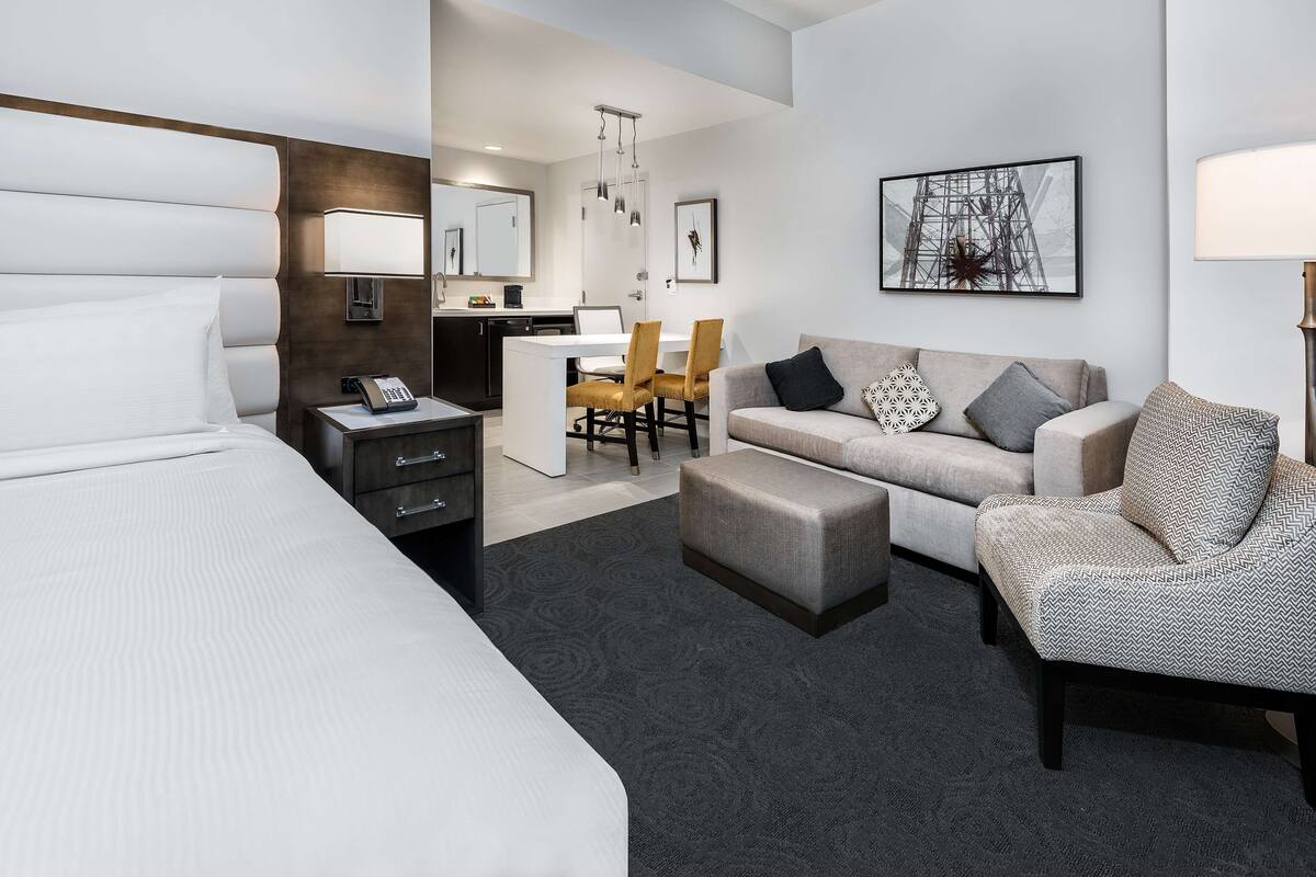 Una habitación de hotel con una cama grande, un sofá, un área de comedor con sillas y un escritorio con teléfono.