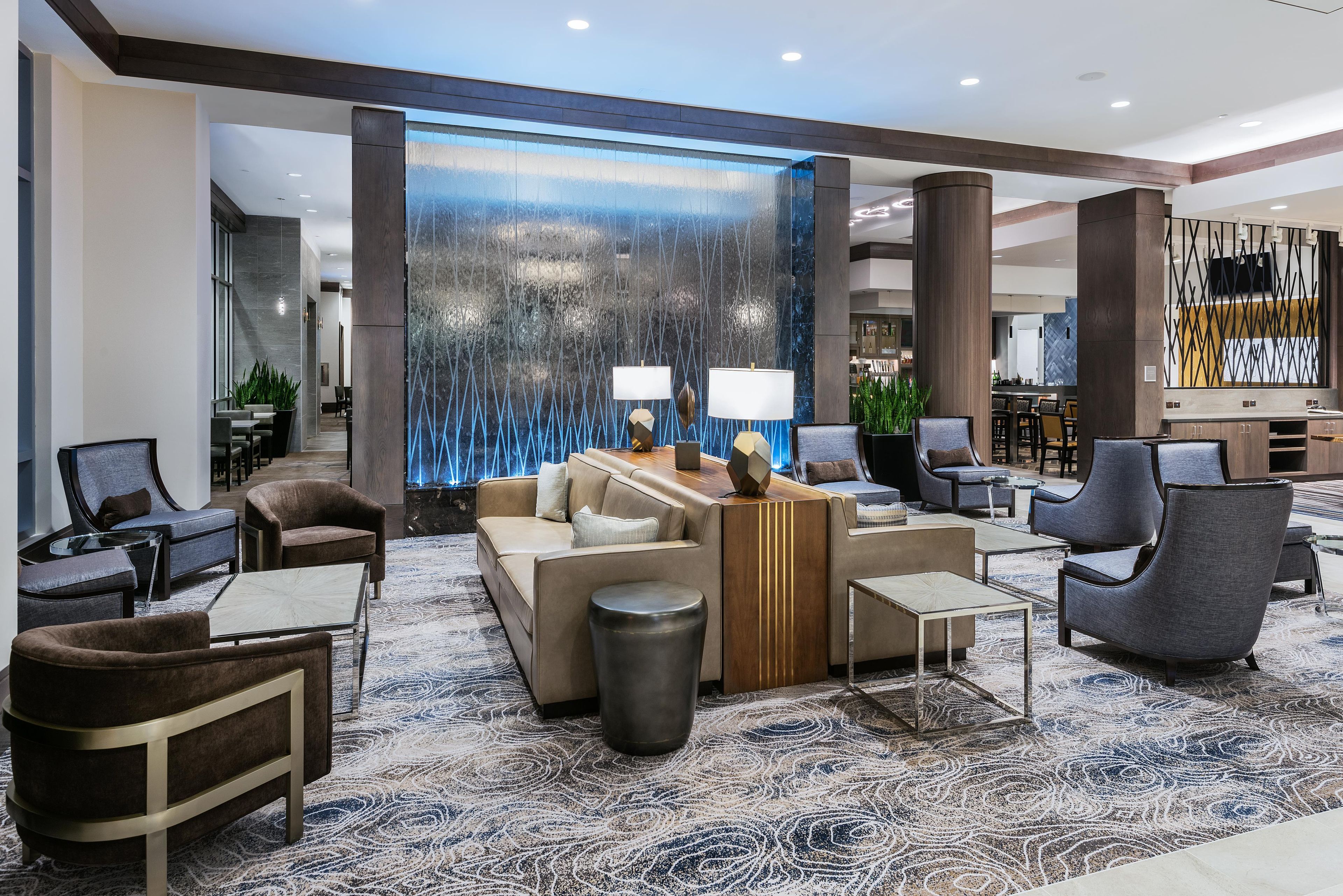 Eine moderne Lobby mit einer Sitzecke, einem Empfangstresen und einer dekorativen Wasserspielelemente.