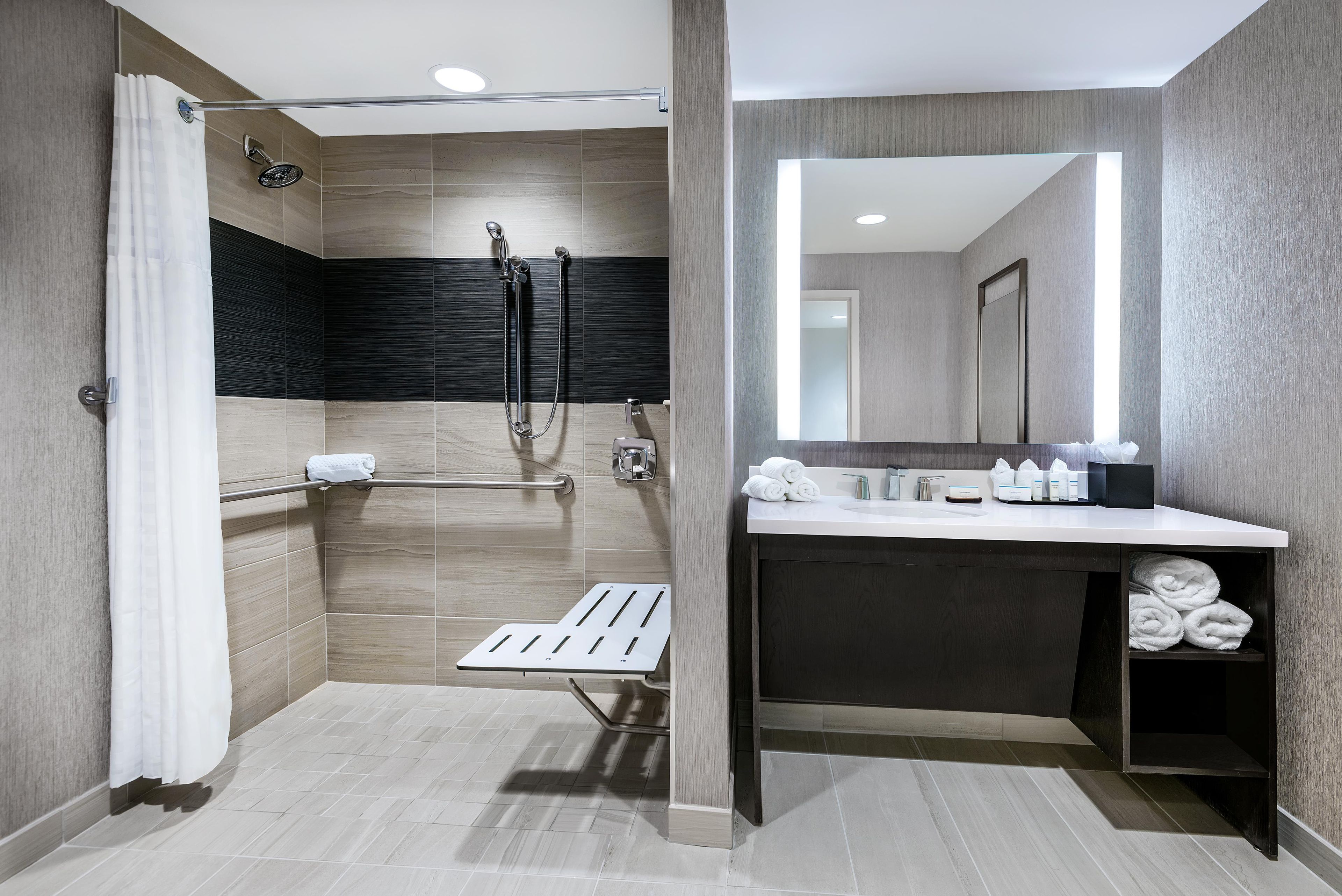 A modern bathroom with a shower, a vanity with a mirror, and a towel rack.