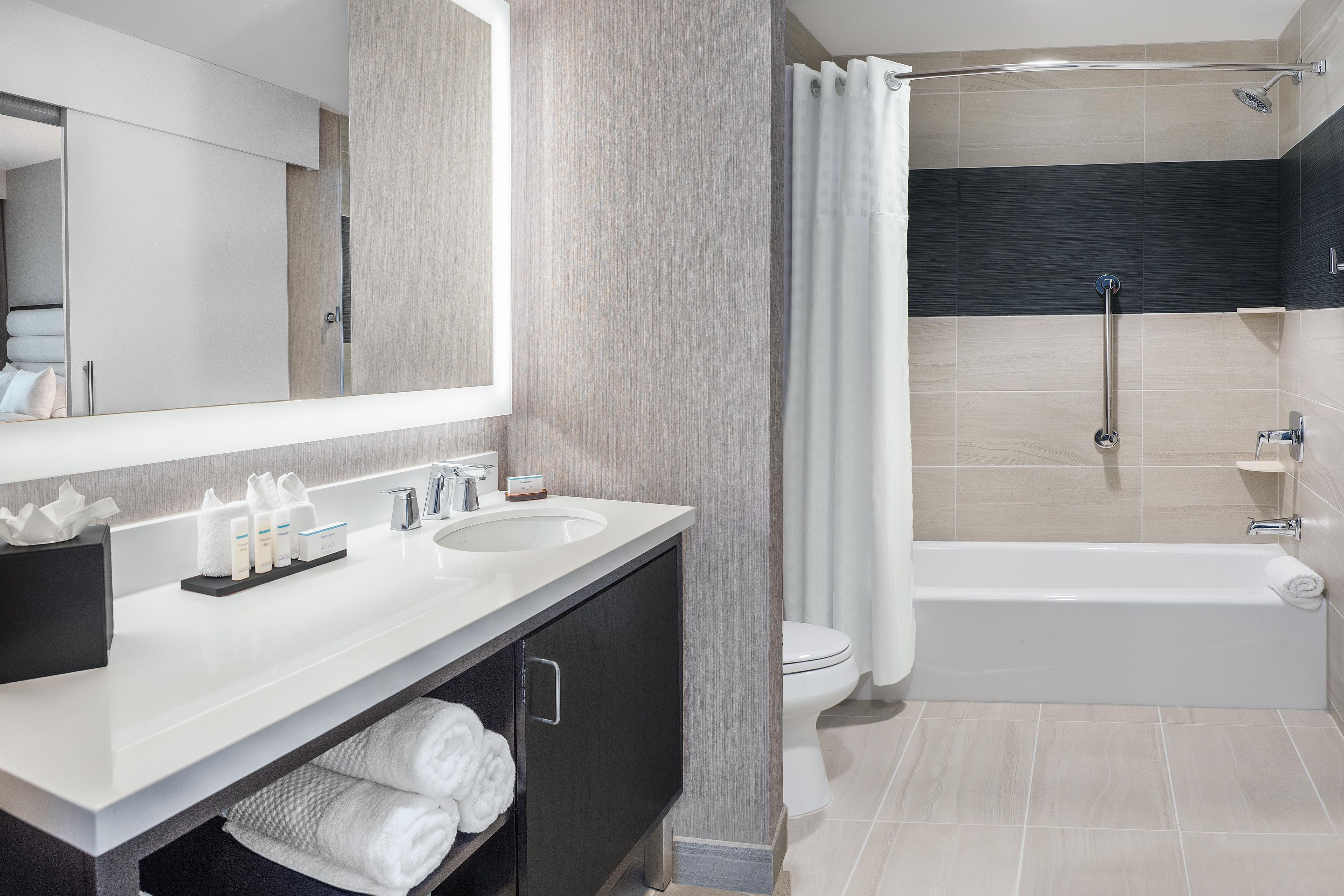 A modern bathroom with a dual sink vanity, a shower with a handheld showerhead, and a toilet.