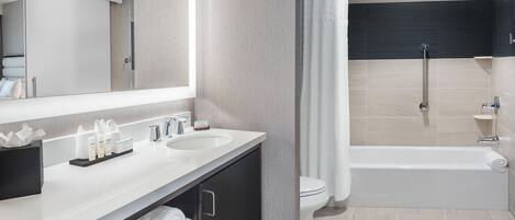 A modern bathroom with a dual sink vanity, a shower with a handheld showerhead, and a toilet.