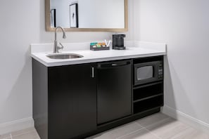 A compact kitchen with a sink, coffee maker, and a microwave.