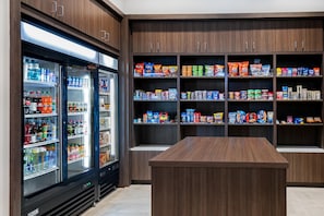 A well-stocked snack and beverage refrigerator with multiple shelves and a central island.
