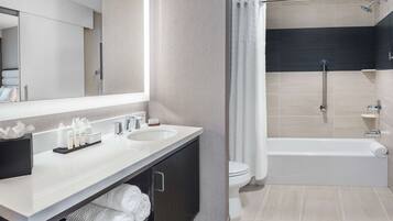 A modern bathroom with two sinks, a large mirror, and a walk-in shower.