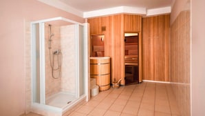 A modern bathroom with a glass-enclosed shower, wooden sauna, and a tiled floor.