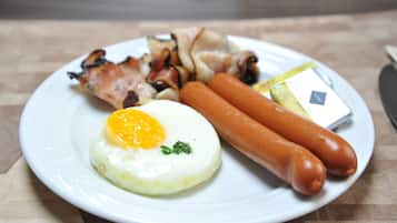 A plate with a fried egg, two sausages, and grilled meat.