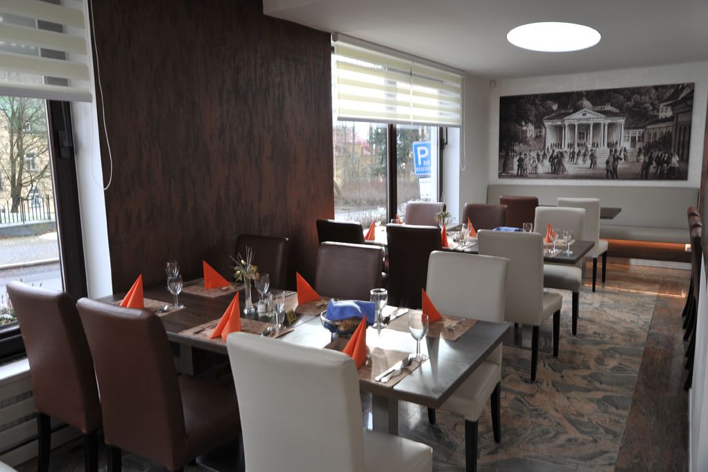 A restaurant with a large dining table, multiple chairs, and a view of the street outside.
