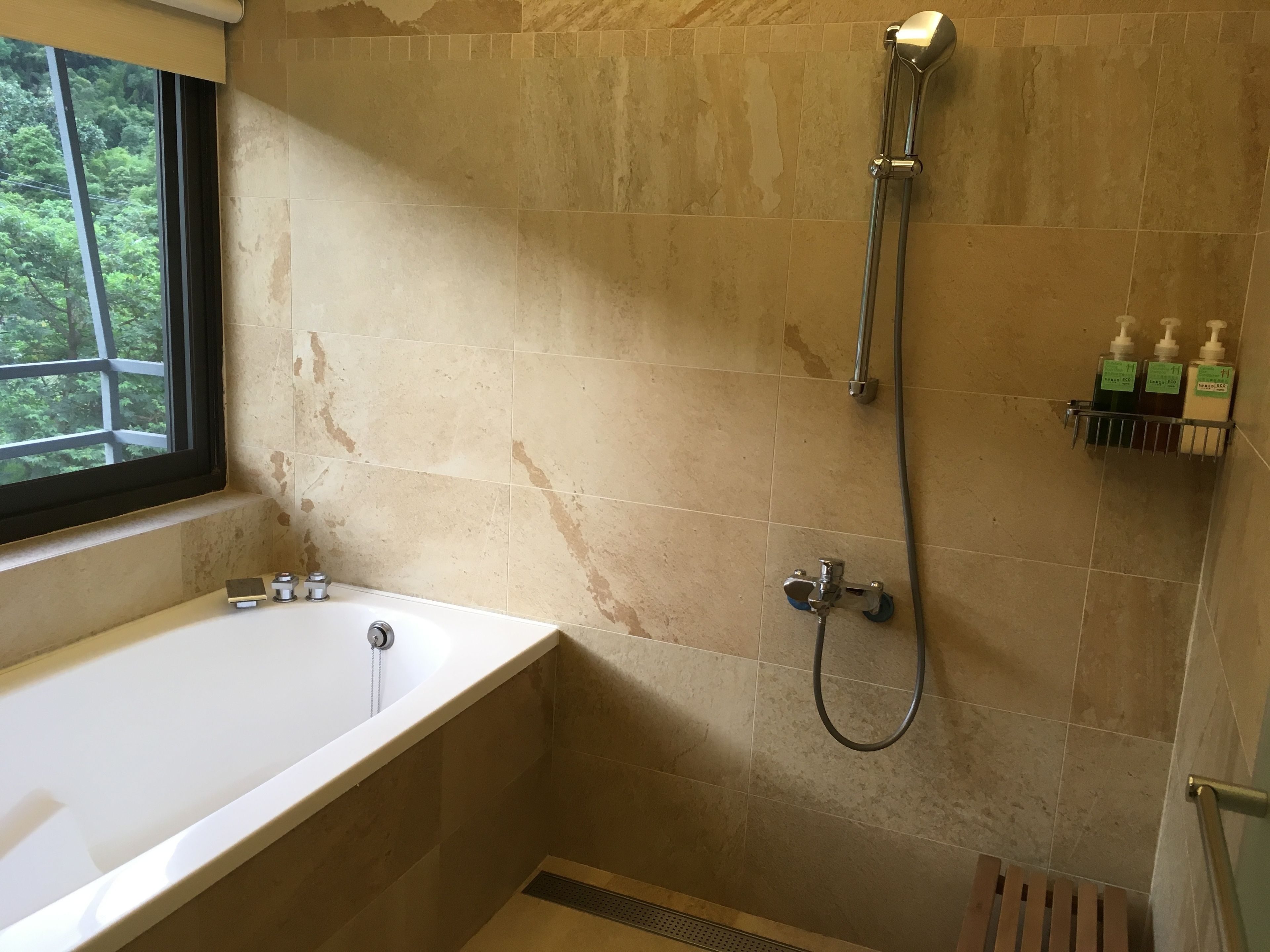 A bathroom with a bathtub, shower, and a window.