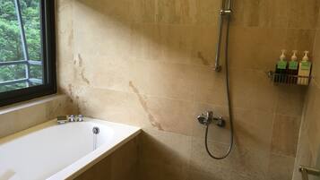 A bathroom with a bathtub, shower, and a window.