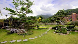 A well-maintained garden with stone pathways, various shrubs, and trees. - Country Road B&B (Toucheng)