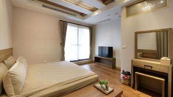 A hotel room with a large bed, a television, a wooden desk, and a mirror.