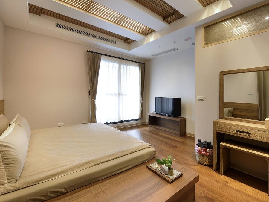 A hotel room with a large bed, a television, a wooden desk, and a mirror.
