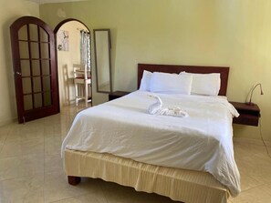 A hotel room with a bed, a nightstand, a chair, and a door. - El Cabarete Spa & Resort (Cabarete)