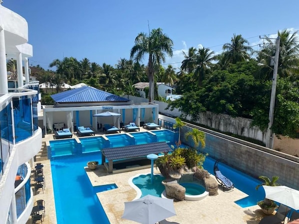 A resort with multiple swimming pools, sun loungers, and a large building with a blue roof.