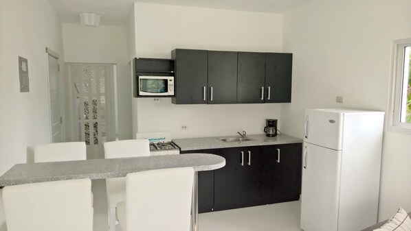 A compact kitchen with a microwave, a coffee maker, and a refrigerator.