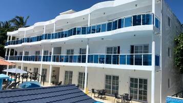Un hôtel à plusieurs étages doté de balcons, d’une piscine et d’un espace extérieur aménagé pour s’asseoir.