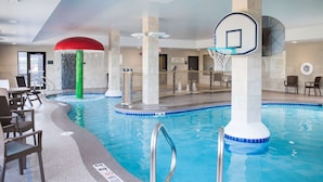 An indoor swimming pool with a basketball hoop, lounge chairs, and a water slide. - Hampton Inn & Suites at Wisconsin Dells Lake Delton (Baraboo)