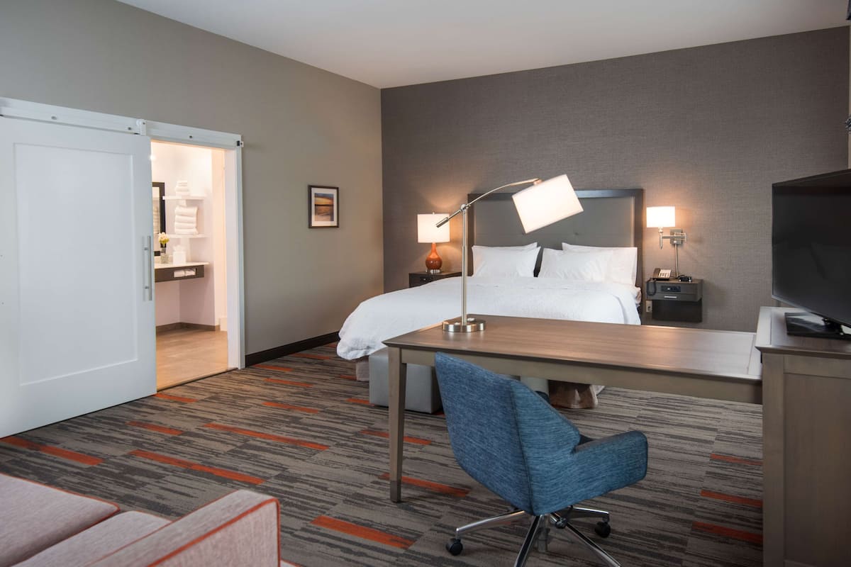 A hotel room with a bed, desk, chair, and two bedside lamps.