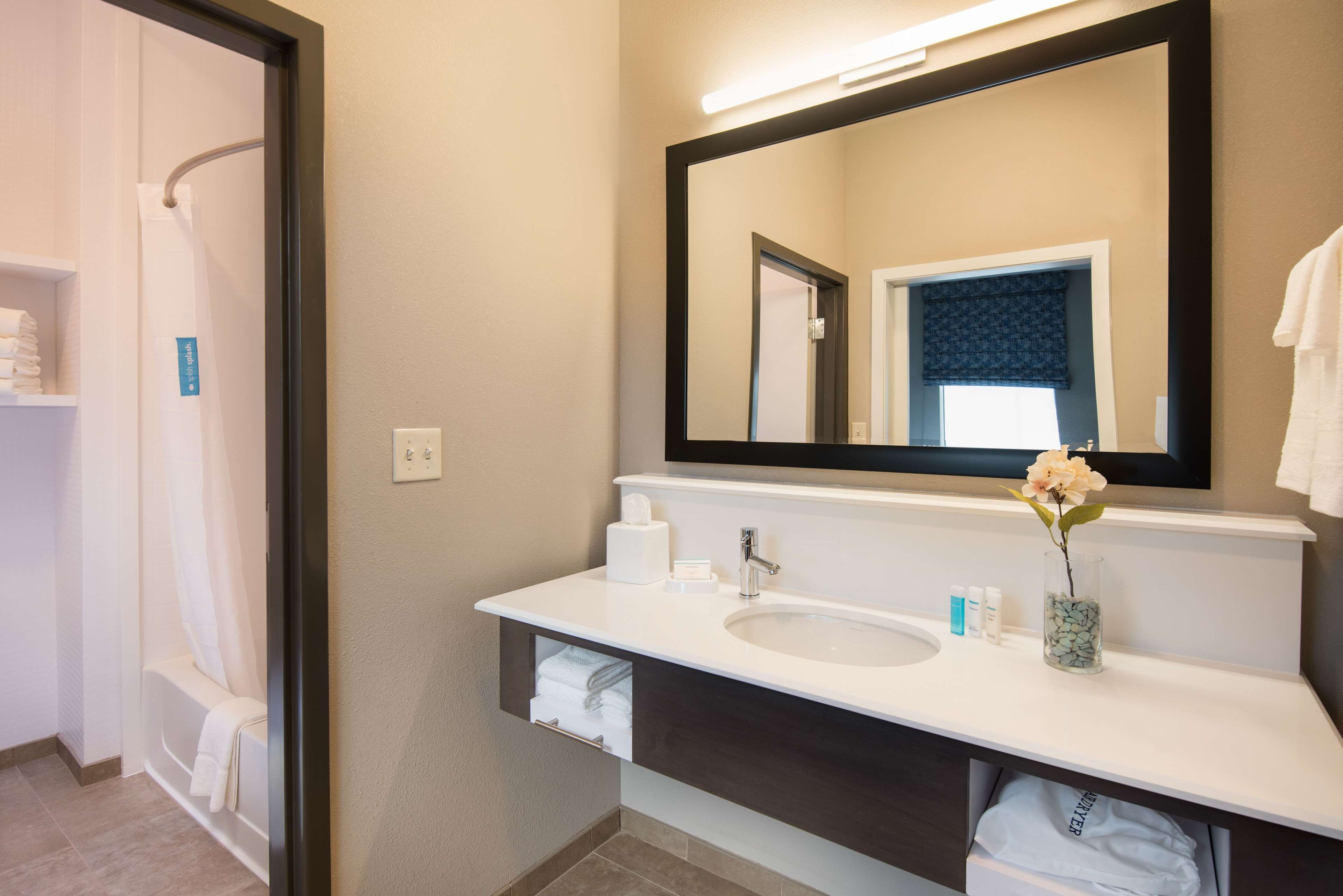 A bathroom with a white sink, dark vanity, and a large mirror.
